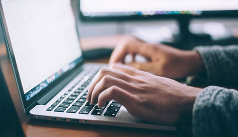 Hands typing on a laptop